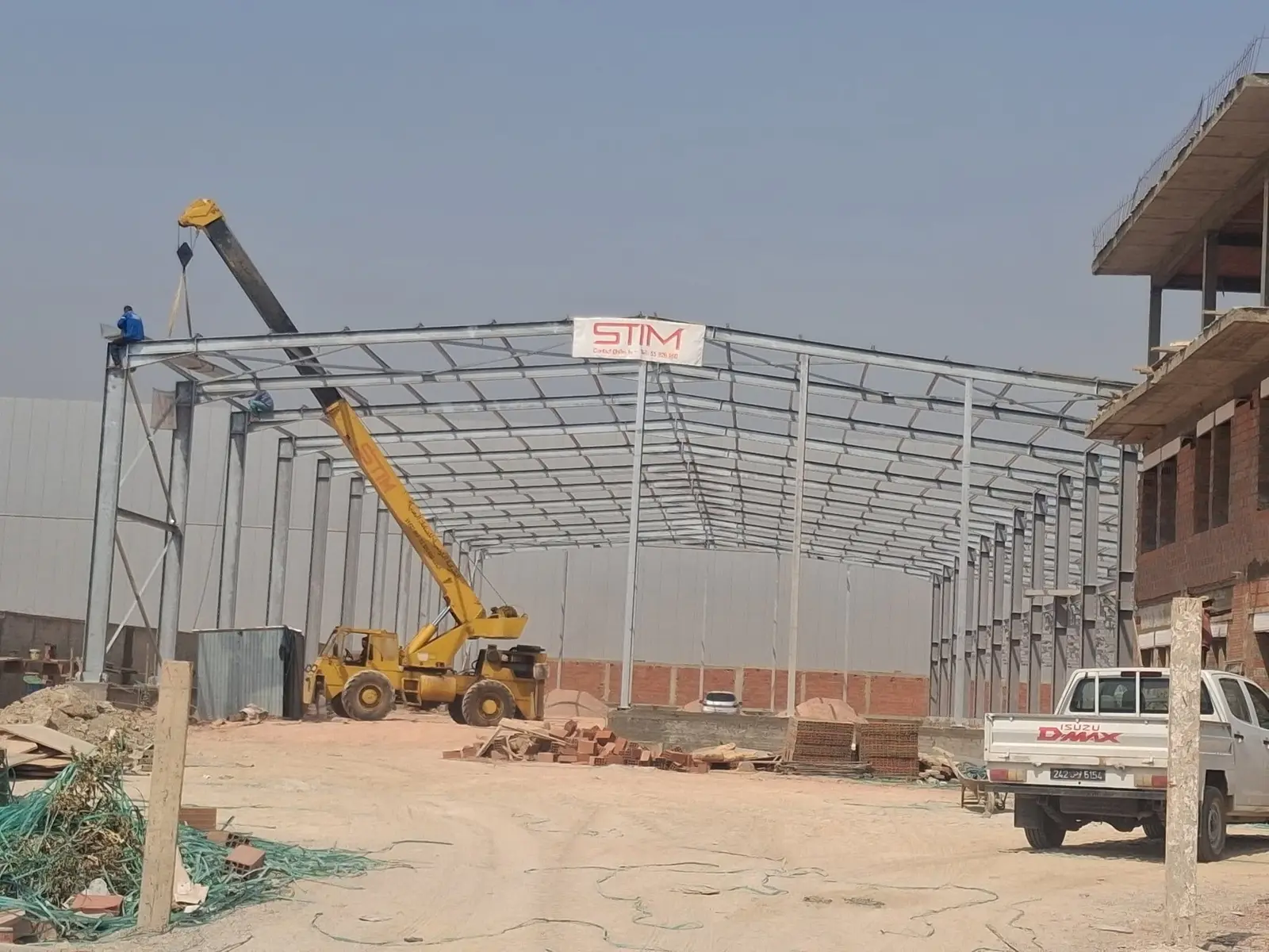 Chantier STIM : montage d'un hangar métallique à la grue mobile